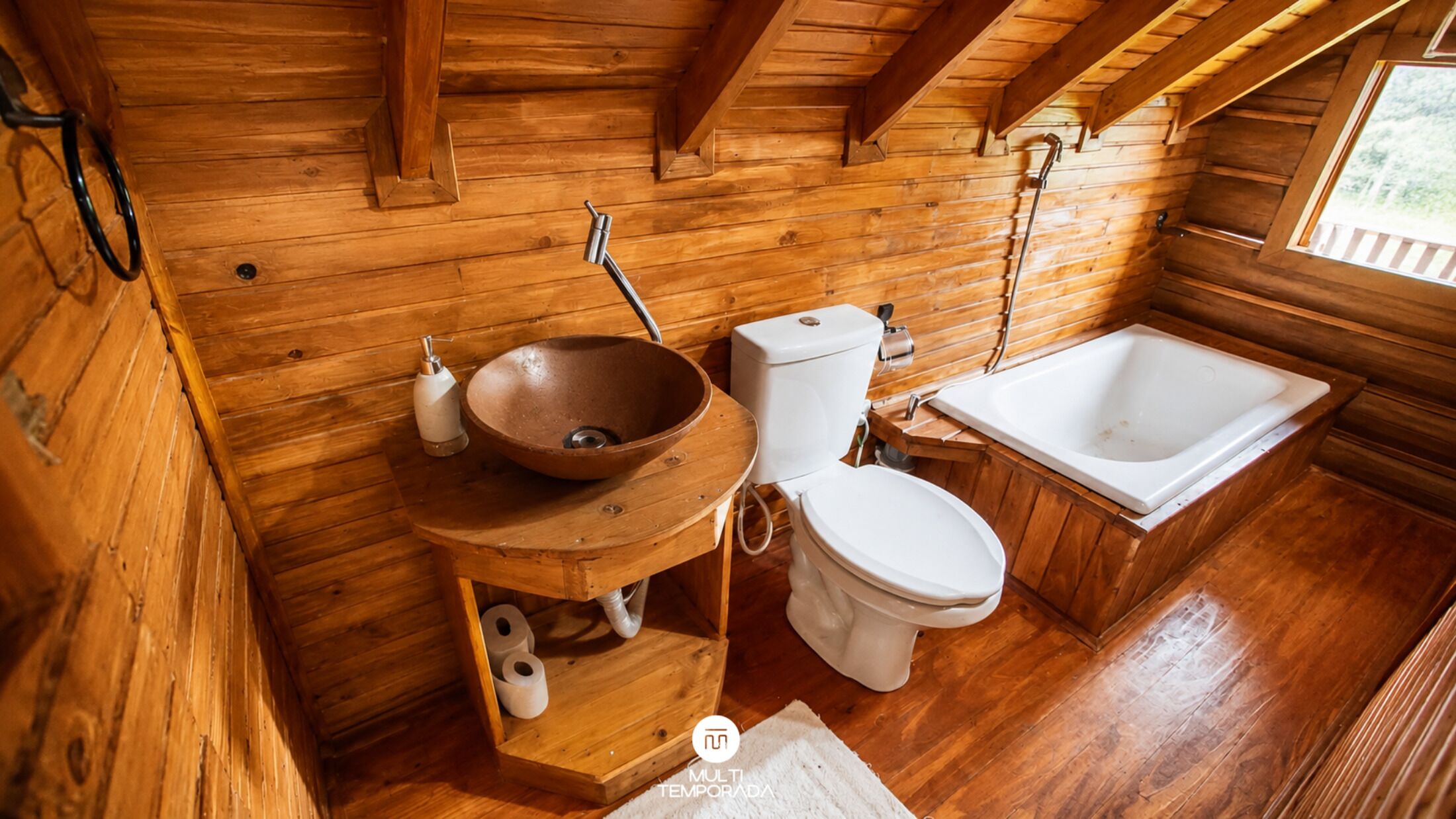 A wooden cabin bathroom with a wooden sink, toilet, and bathtub.