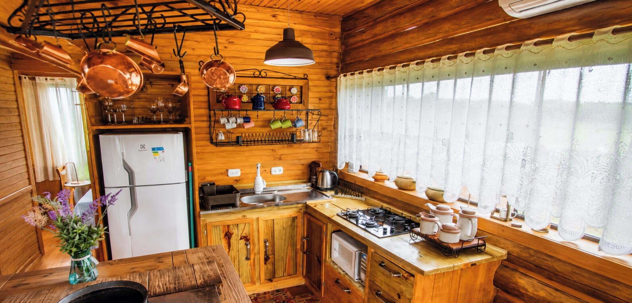 A compact kitchen with wooden cabinets, a refrigerator, a sink, and a stove.