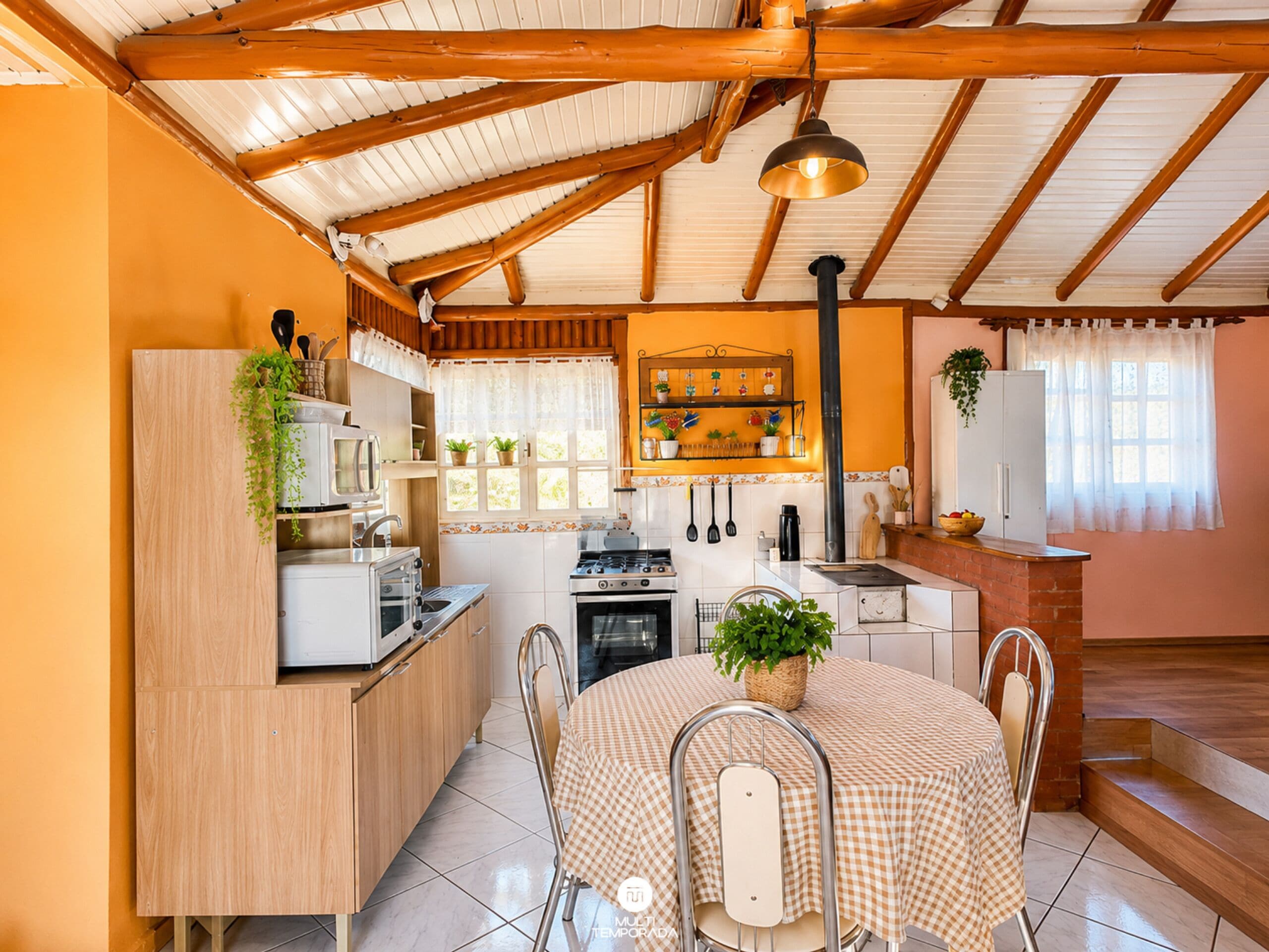 Uma cozinha com vigas de madeira, uma mesa de jantar com cadeiras e um lustre.