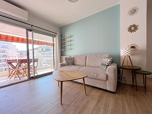 A modern living room with a sofa, a coffee table, and a small side table. - Viva Riviera Sunny Apartment with Balcony (Cannes)