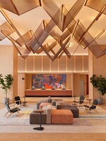 A modern lobby with a geometric ceiling design, a reception desk, and seating area.