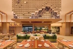 A restaurant with a buffet setup, wooden furniture, and a decorative ceiling.