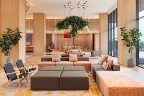 A spacious lobby with a central seating area, a large tree, and a modern chandelier. - Asai Gamuda Cove (Banting)