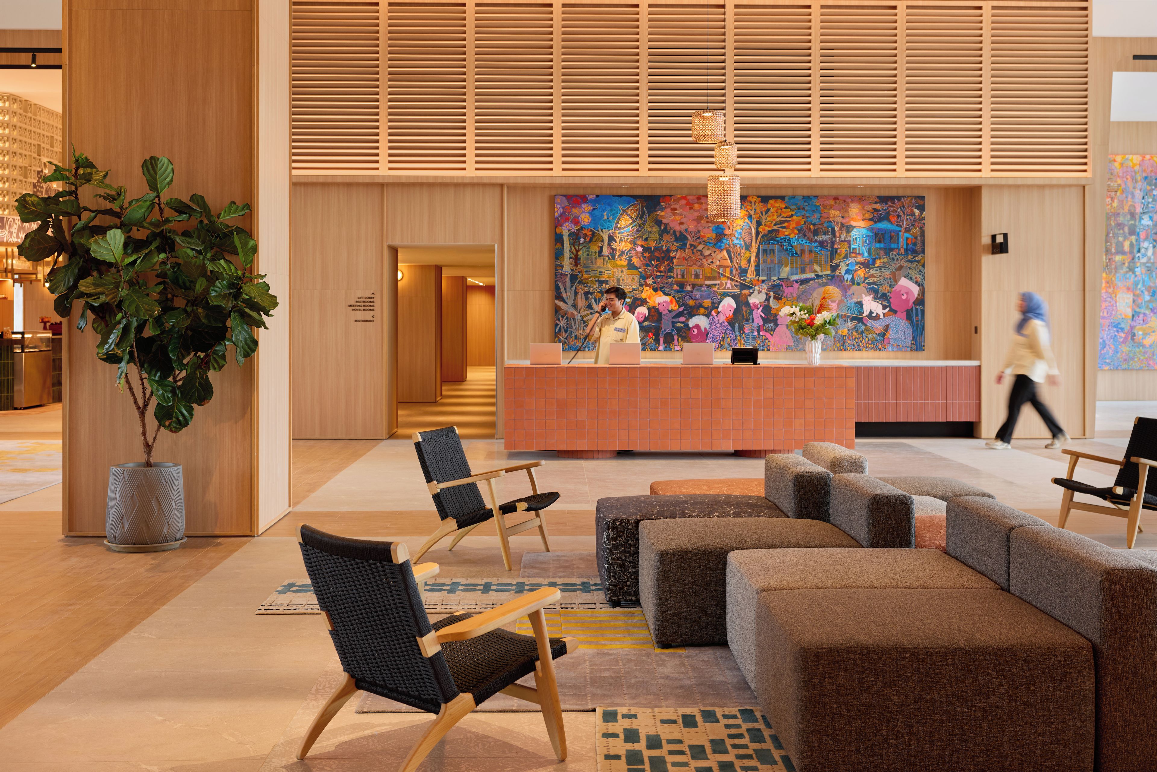 A modern lobby with a reception desk, seating area, and a large mural.