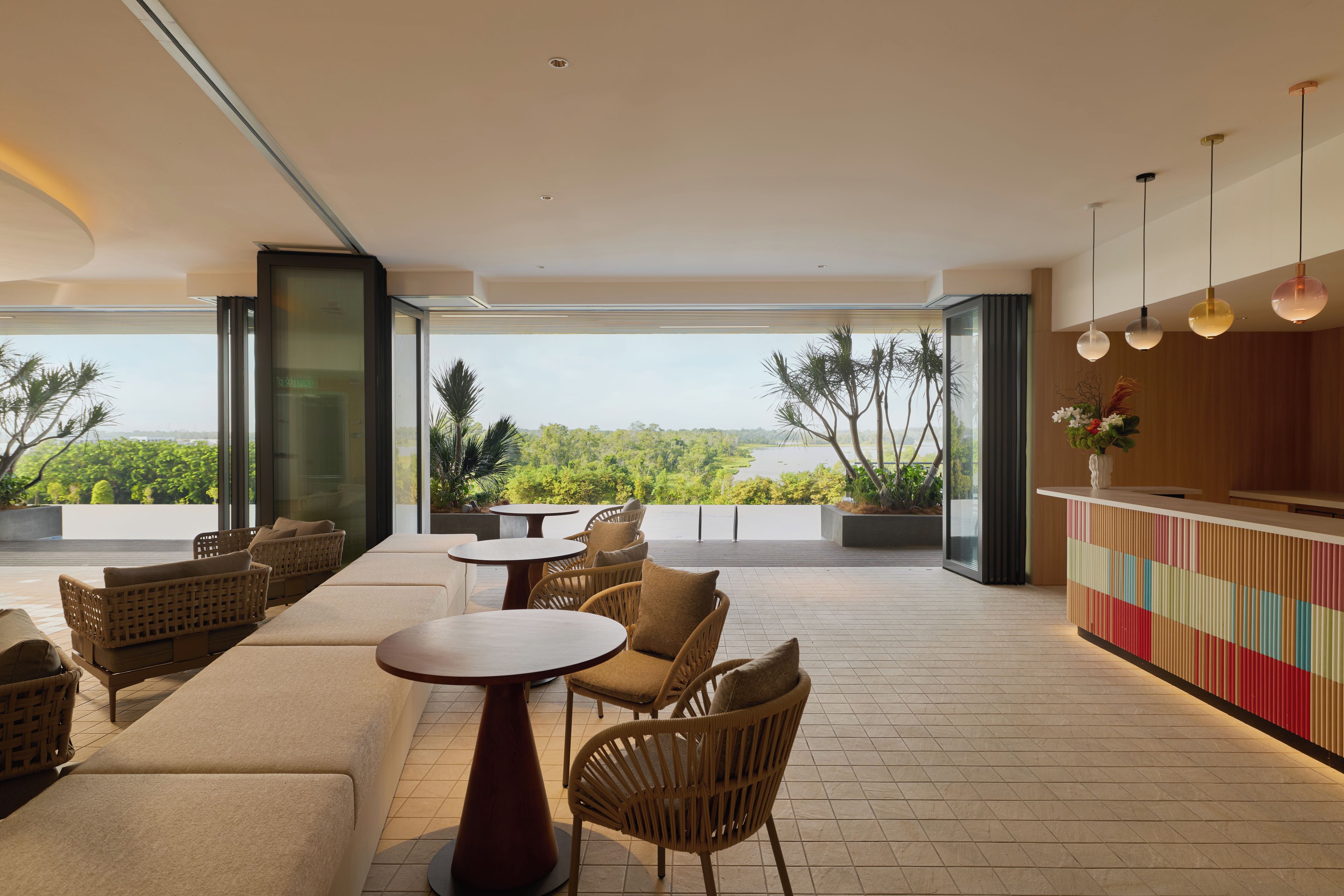 A modern outdoor seating area with wicker furniture, a round table, and a bar with a colorful design.