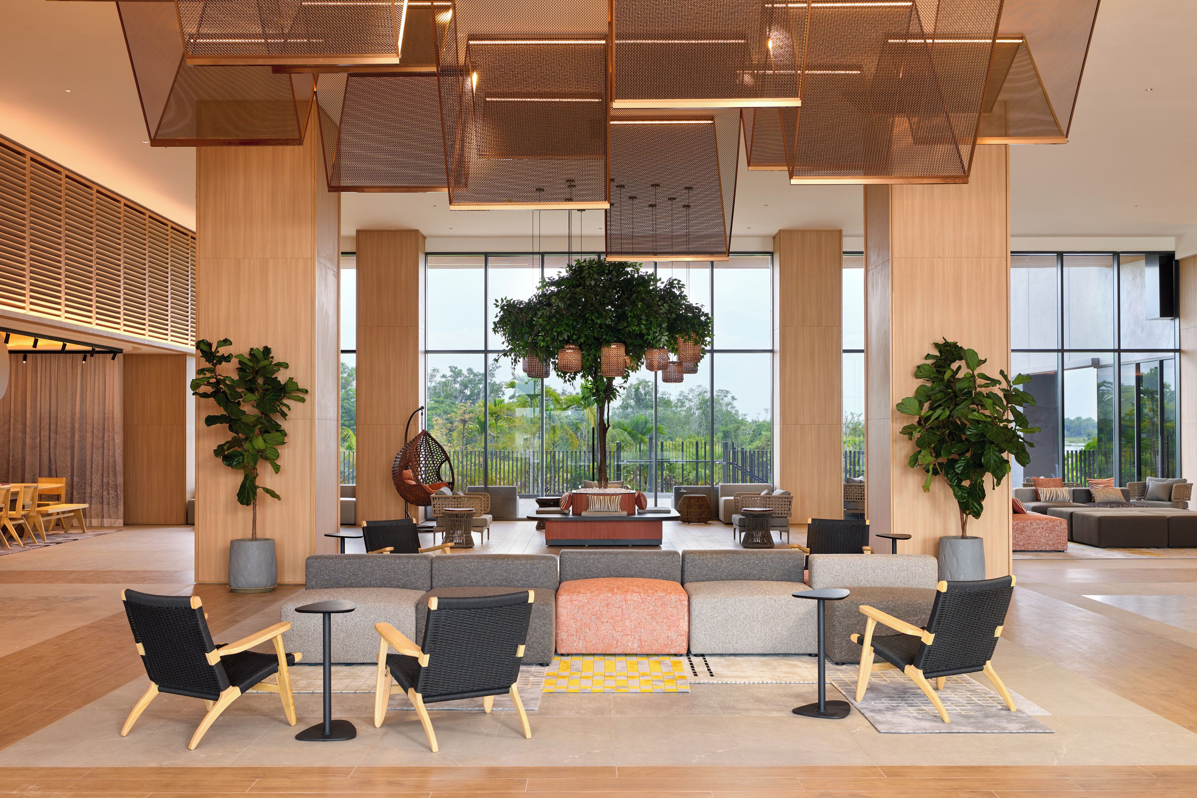 A spacious lobby with a seating area, large windows, and a view of greenery outside.