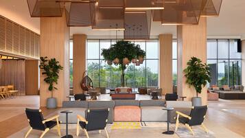 A spacious lobby with a seating area, large windows, and a view of greenery outside.