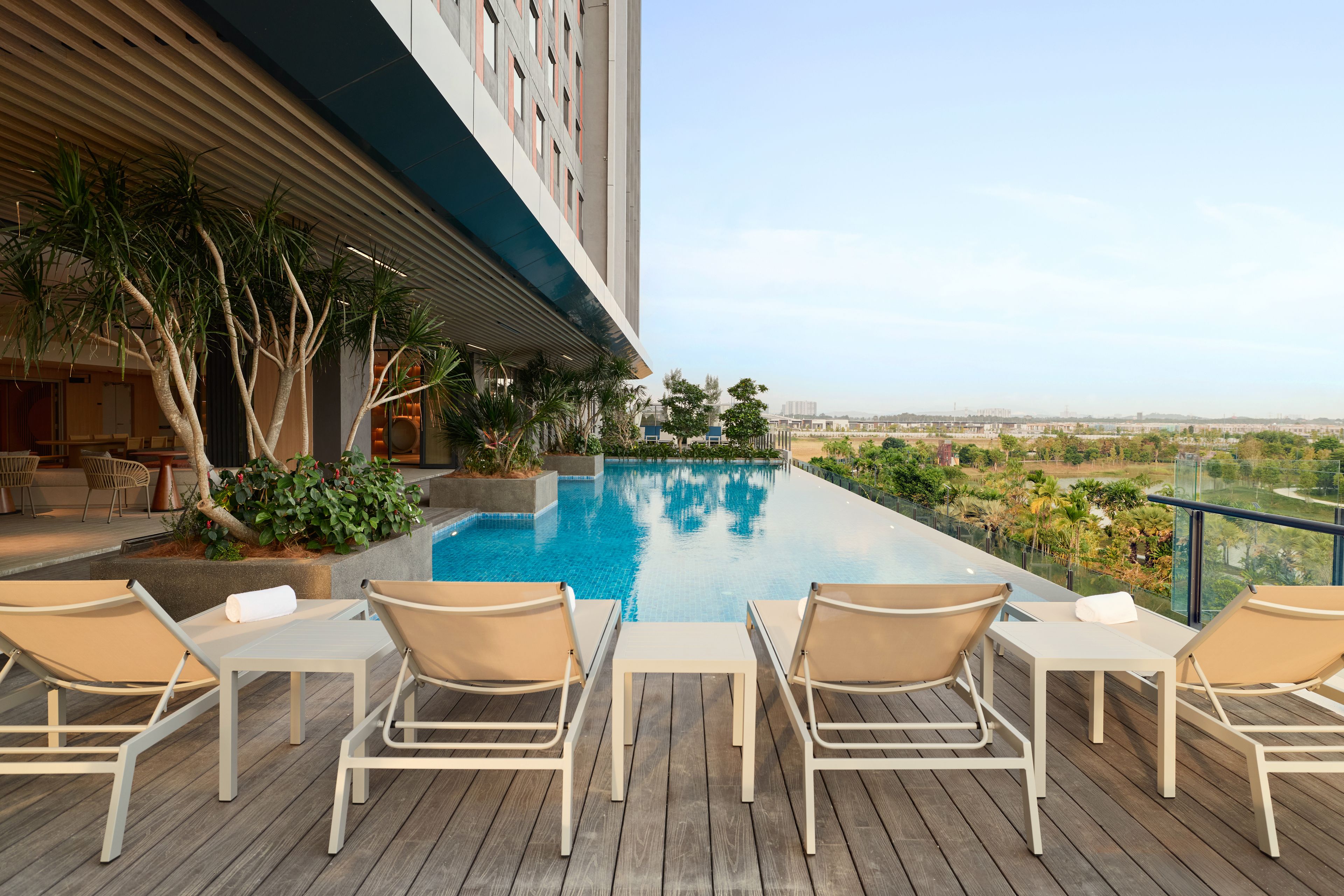 A rooftop pool area with lounge chairs and a view of the cityscape.