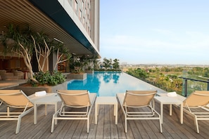 A rooftop pool area with lounge chairs and a view of the cityscape.