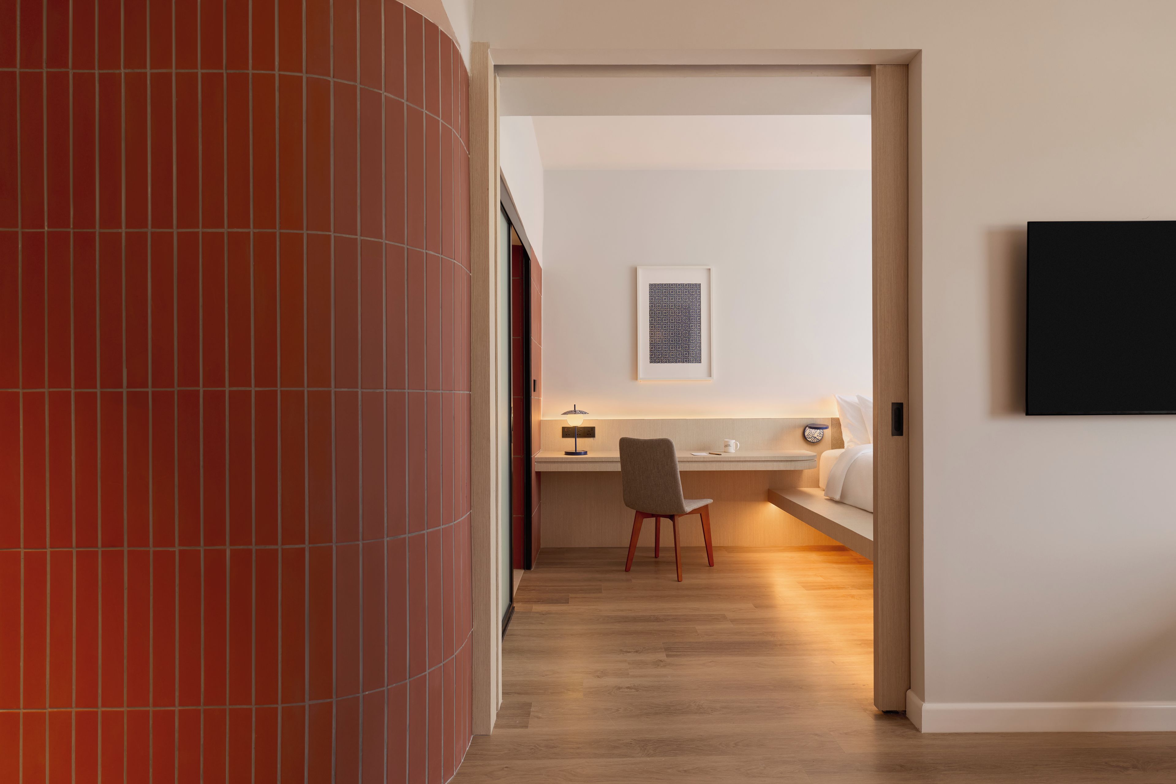 Un interior moderno con piso de madera, un escritorio con una silla y un cuadro en la pared.