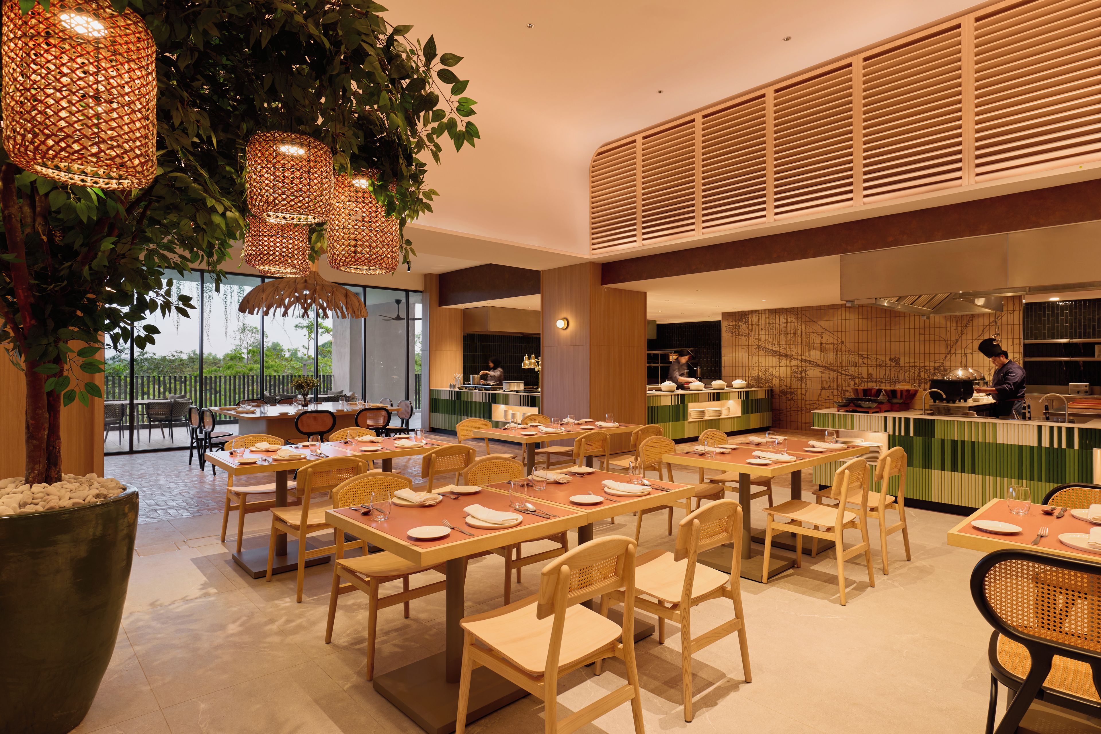 Un restaurant doté de nombreuses tables et chaises, d’un grand arbre et de guirlandes lumineuses.