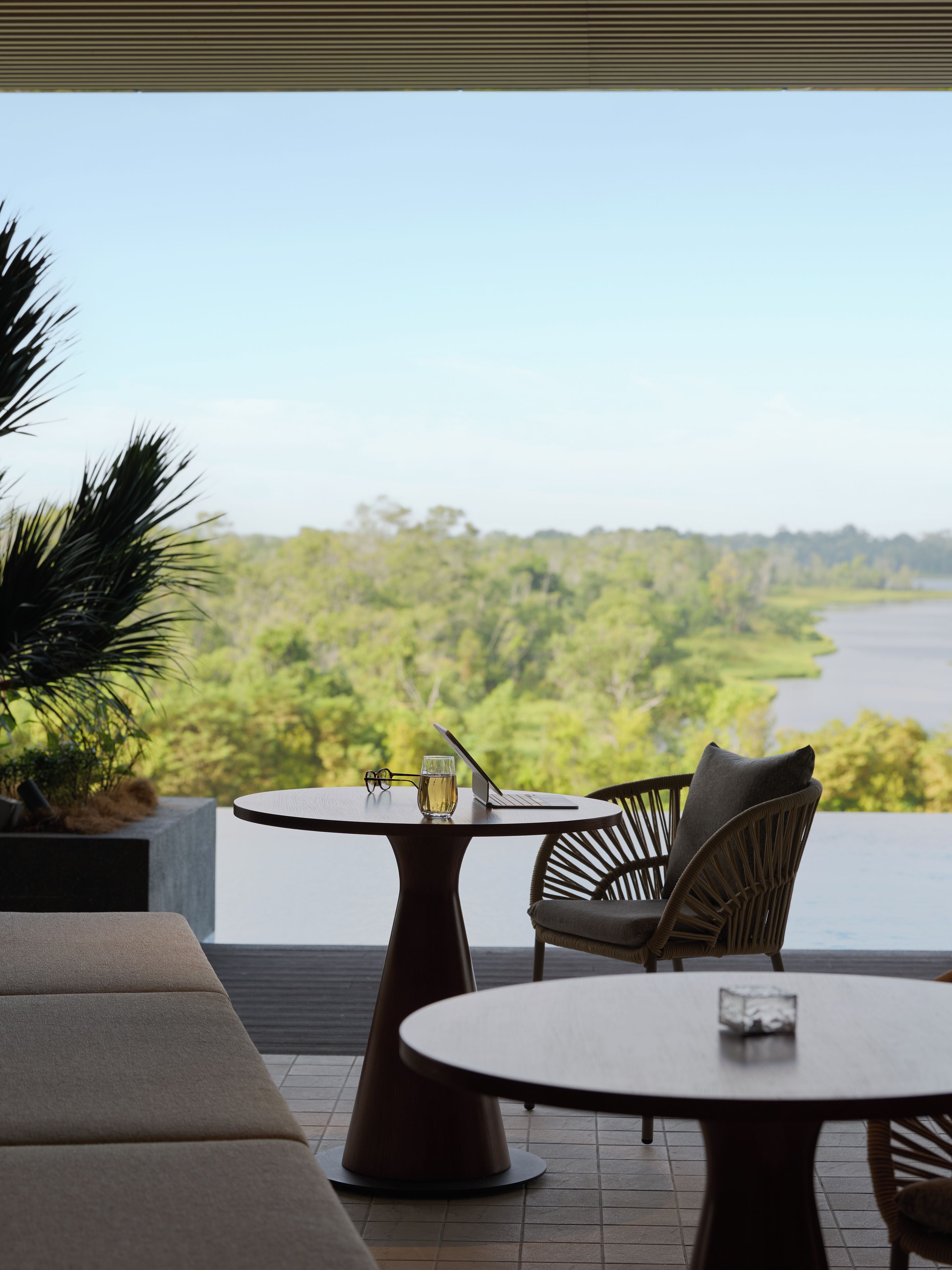 A terrace with a round table, two chairs, a glass of water, and a laptop.