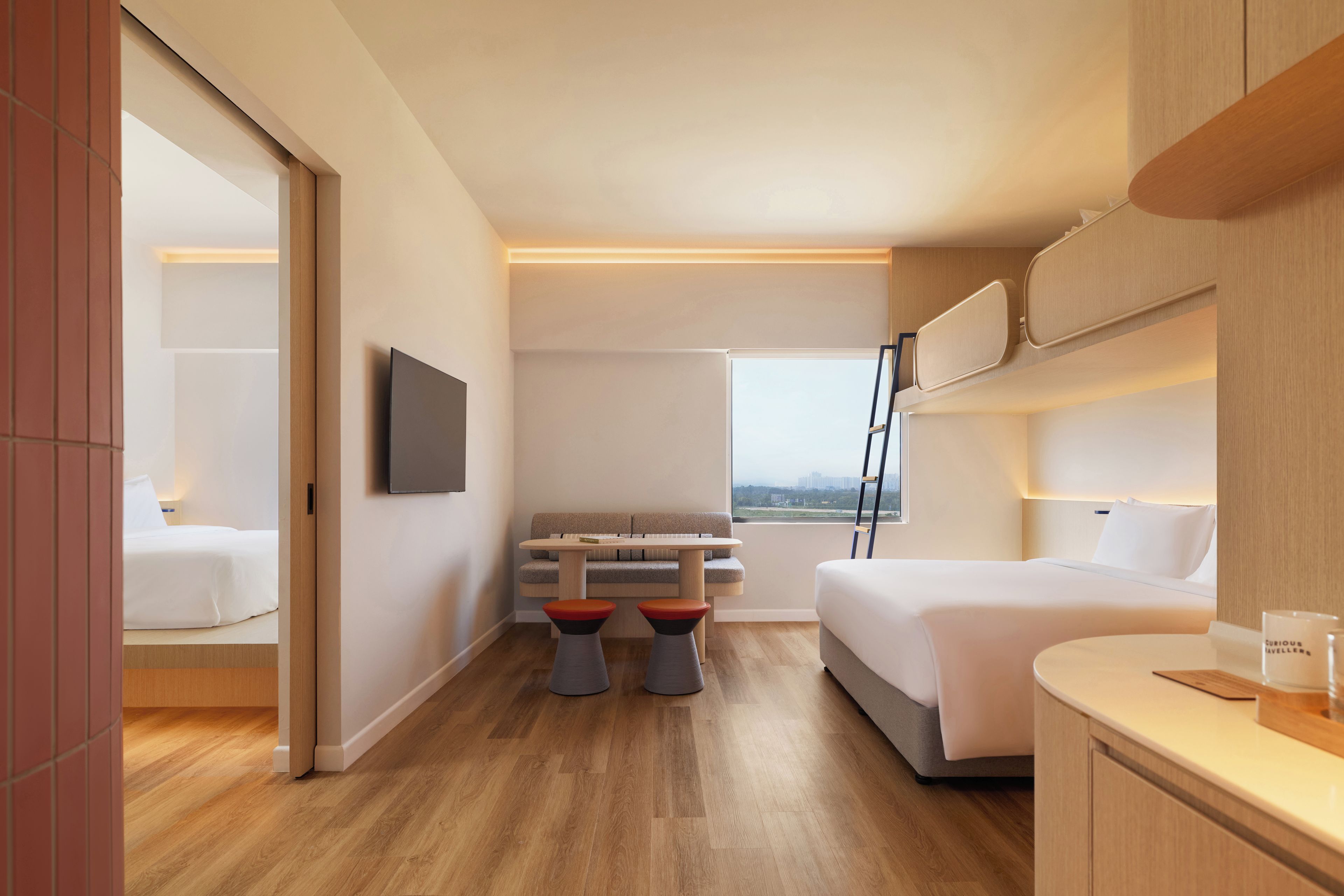 A modern hotel room with a bed, a sofa, a small table, and a TV.