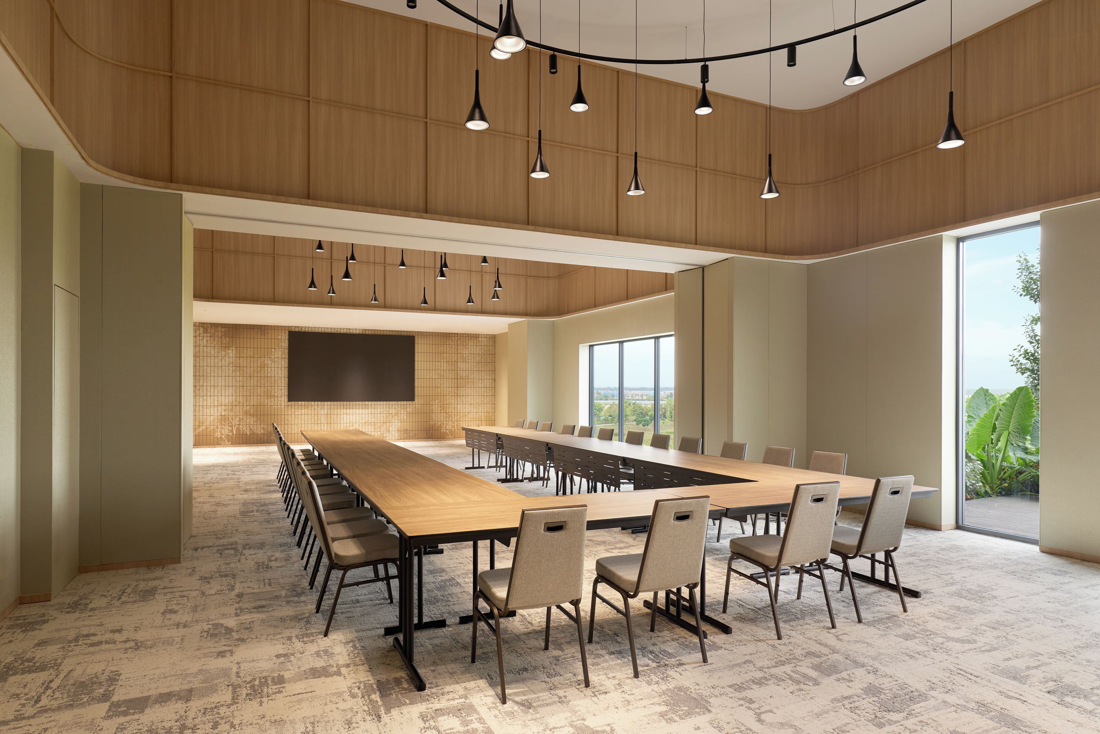 A conference room with a long table, chairs, and pendant lighting.