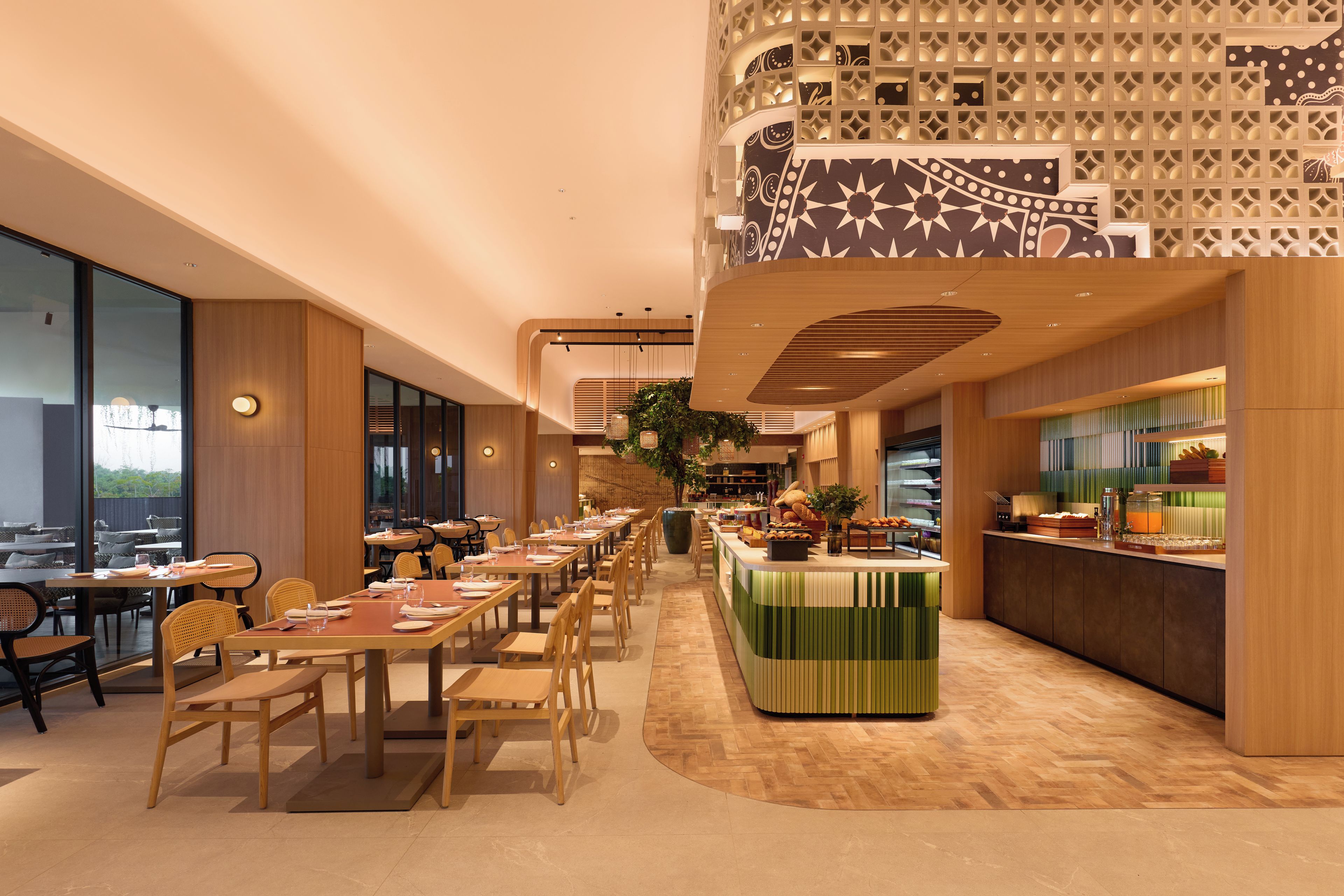 A modern restaurant interior with a long dining table, wooden chairs, and a buffet area.