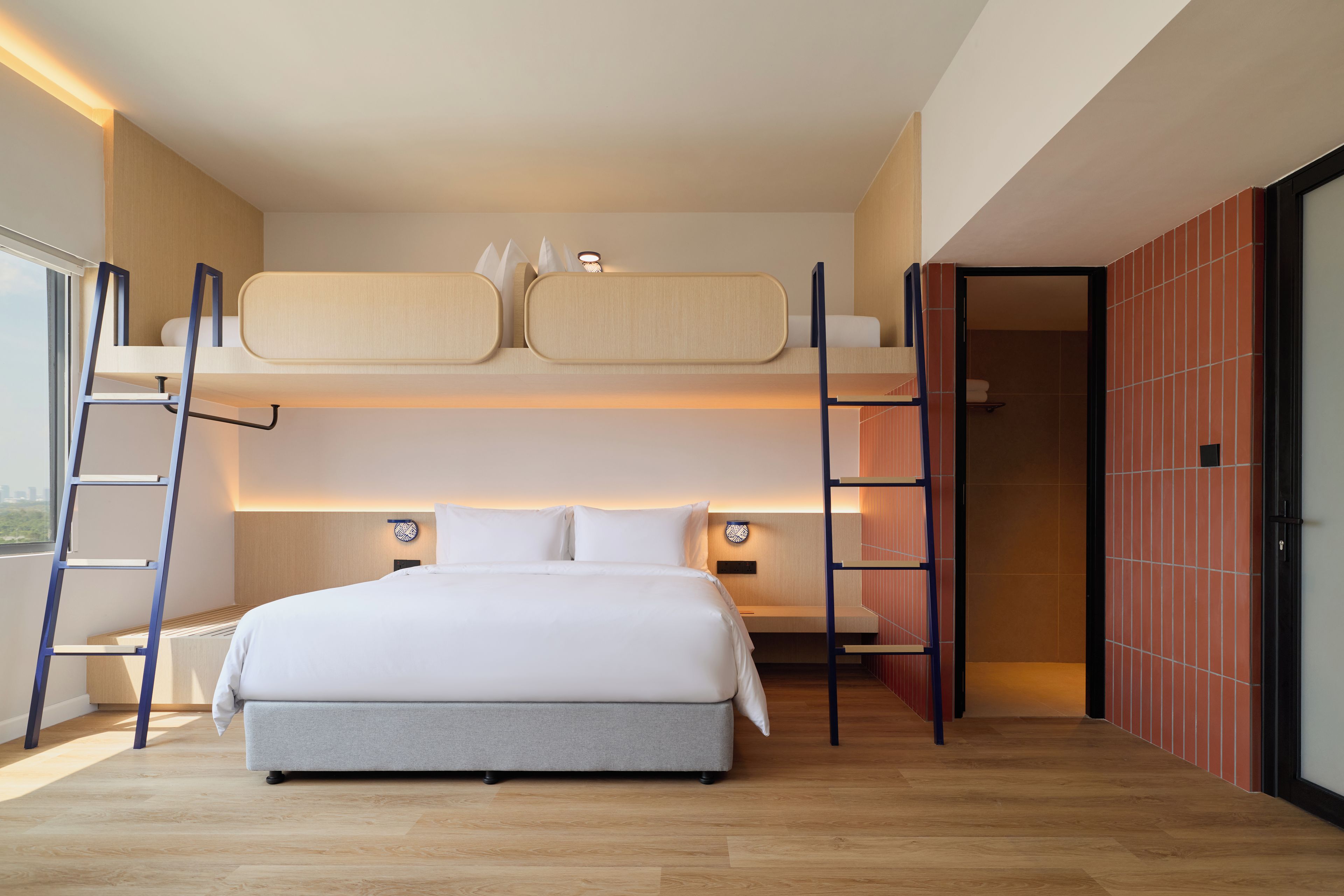 Una habitación de hotel moderna con literas, un escritorio y vistas a la ciudad.