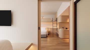 A modern hotel room with a bed, a desk, and a kitchenette.