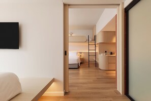 A modern hotel room with a bed, a desk, and a kitchenette. - Asai Gamuda Cove (Banting)
