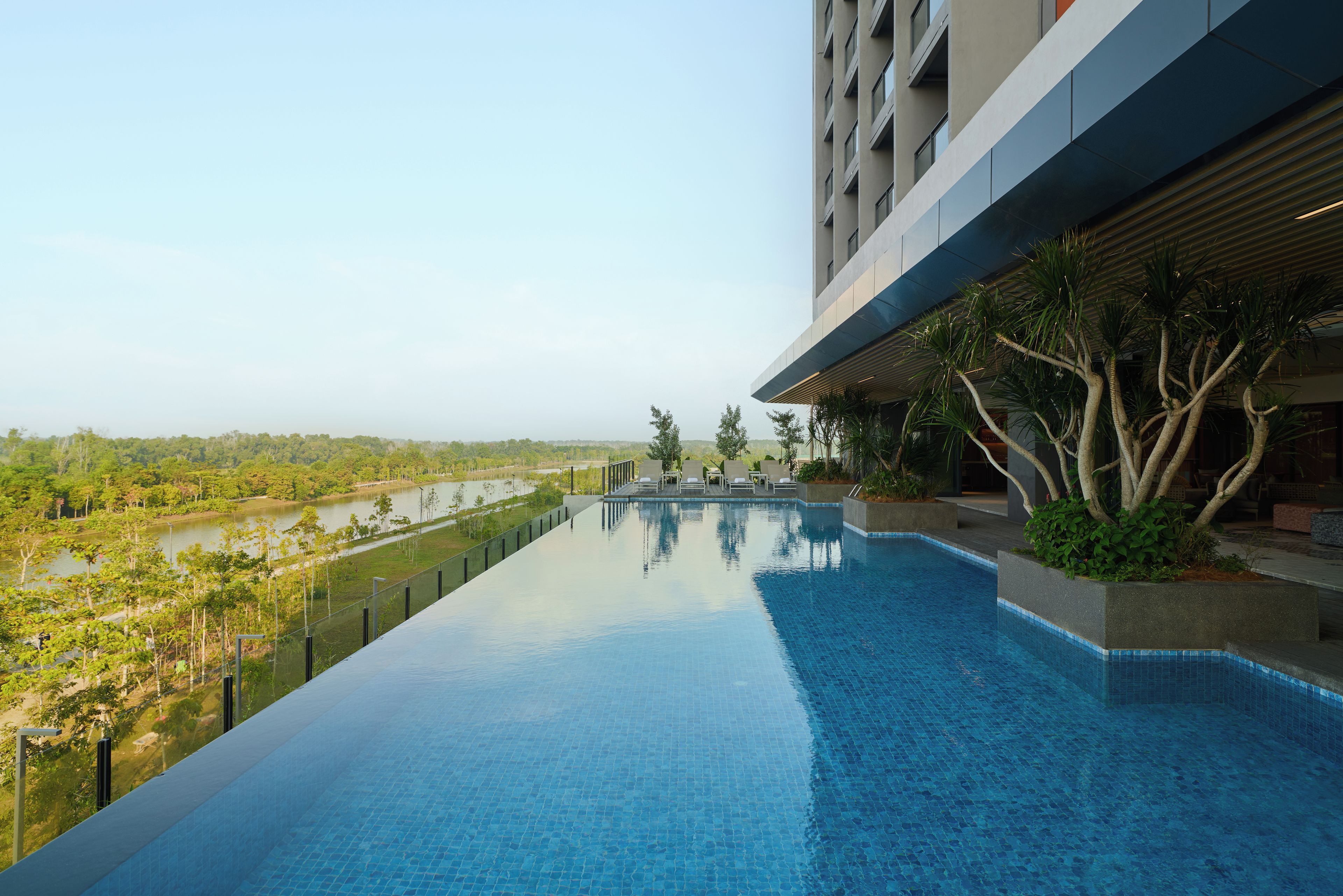 Un hotel moderno con piscina infinita en la azotea y vistas a un paisaje natural.