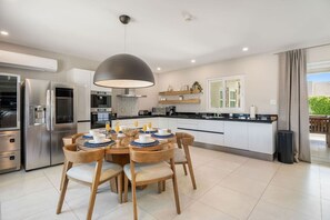 A modern kitchen with a dining area, stainless steel appliances, and a large pendant light. - NEW 3BR Luxe Villa in Esmeralda by Signature Stays (Noord)
