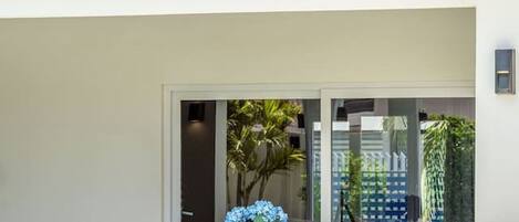 A poolside area with a wooden table and chairs, a tiled pool, and a covered seating area with a view of the pool.