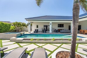Una casa moderna con piscina, mobiliario exterior y un jardín bien cuidado.