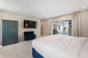 Ein Schlafzimmer mit einem großen Bett, einem an der Wand montierten Fernseher, einem Kleiderschrank und Blick auf Pool und Außenbereich.