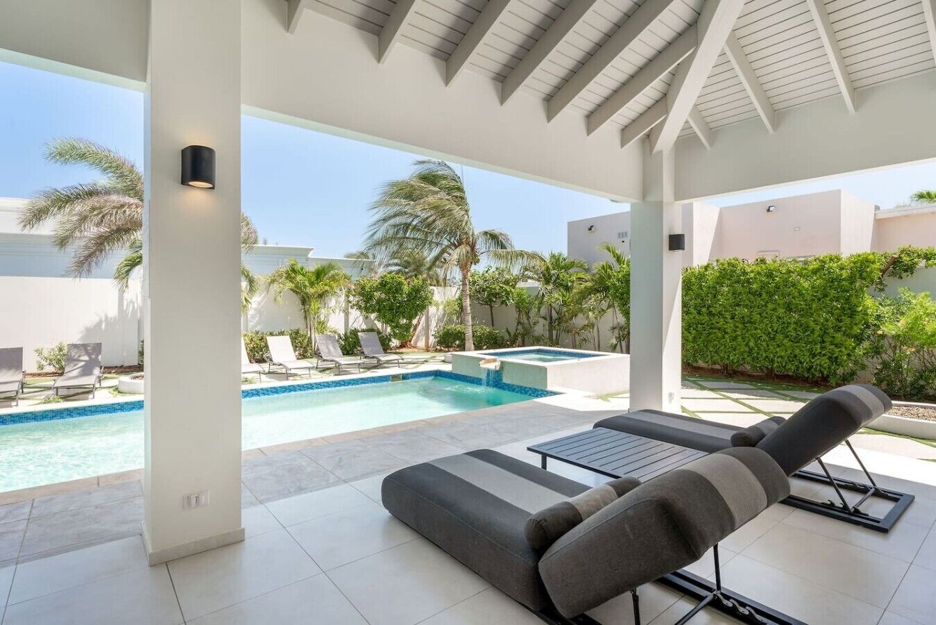 Ett takförsett utomhusområde med en pool, solstolar och utsikt över ett bostadsområde.