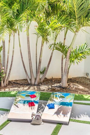 A garden with palm trees and a paved area with a bench and a small table. - NEW 3BR Luxe Villa in Esmeralda by Signature Stays (Noord)