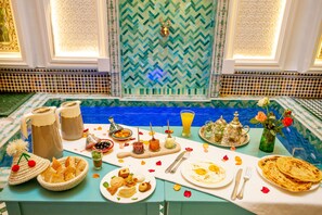 A dining table set with traditional Moroccan dishes, tea, and a decorative vase with roses. - Riad Dar Lefna (Marrakech)