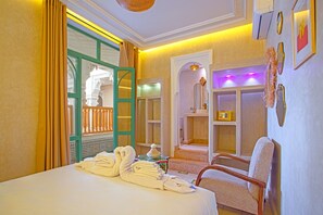 Een hotelkamer met een bed, een stoel, een badkamer en een douche.