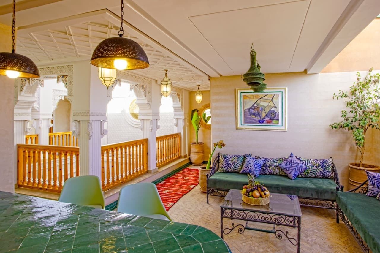 A room with a green sofa, a dining table with chairs, hanging lamps, and a decorative wall piece.