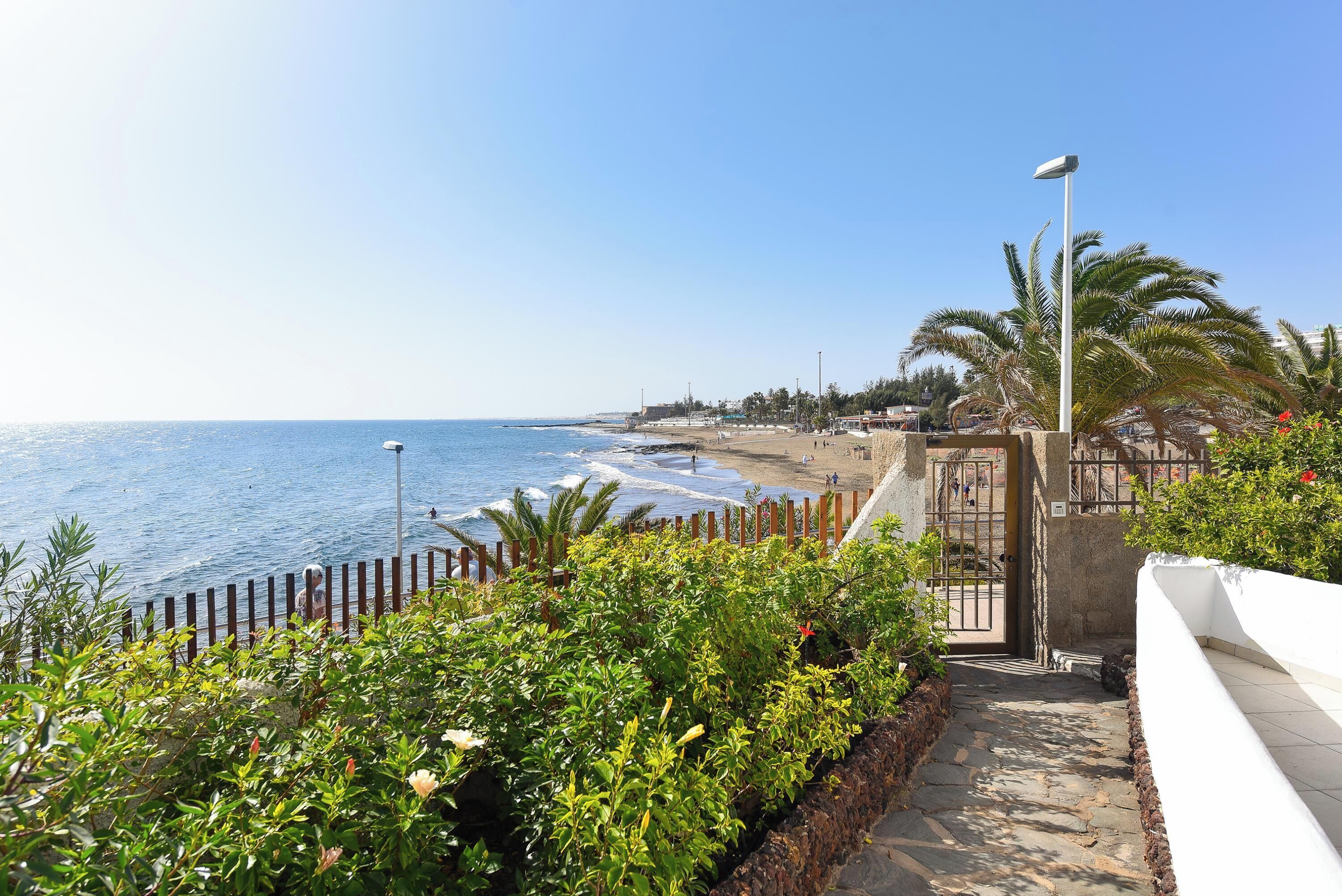 Une promenade en bord de mer offrant une vue sur la mer, un sentier pavé et une clôture.