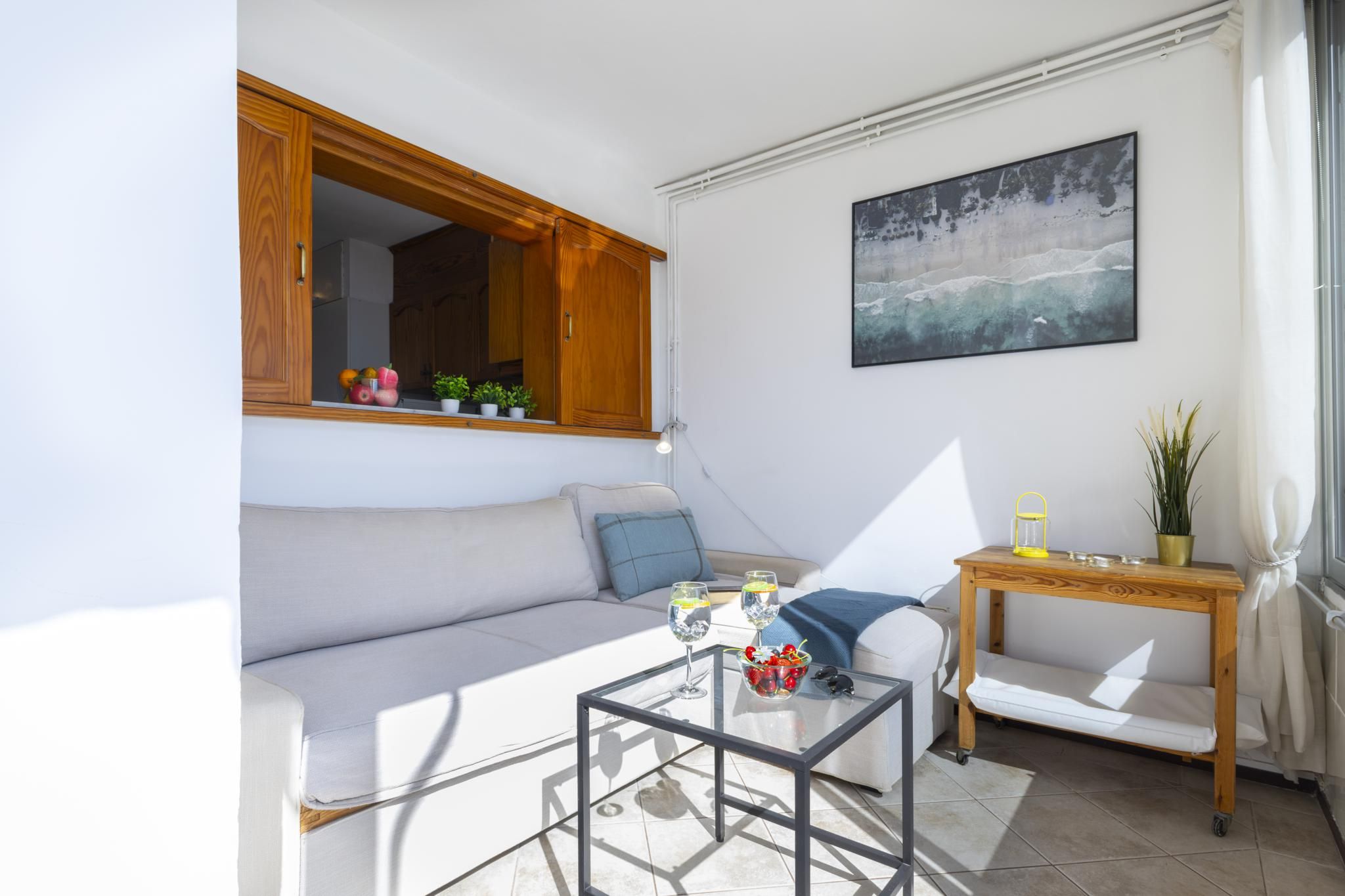 Un salon moderne avec un canapé, une table basse en verre et une petite table en bois sur laquelle est posée une lampe.