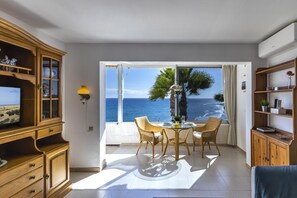 A room with a view of the ocean, a dining table with chairs, a TV, and wooden furniture. - Nueva Suecia 421 by VillaGranCanaria (Maspalomas)