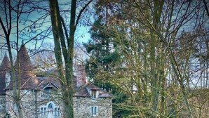 A stone building with a tower, surrounded by trees and grass.