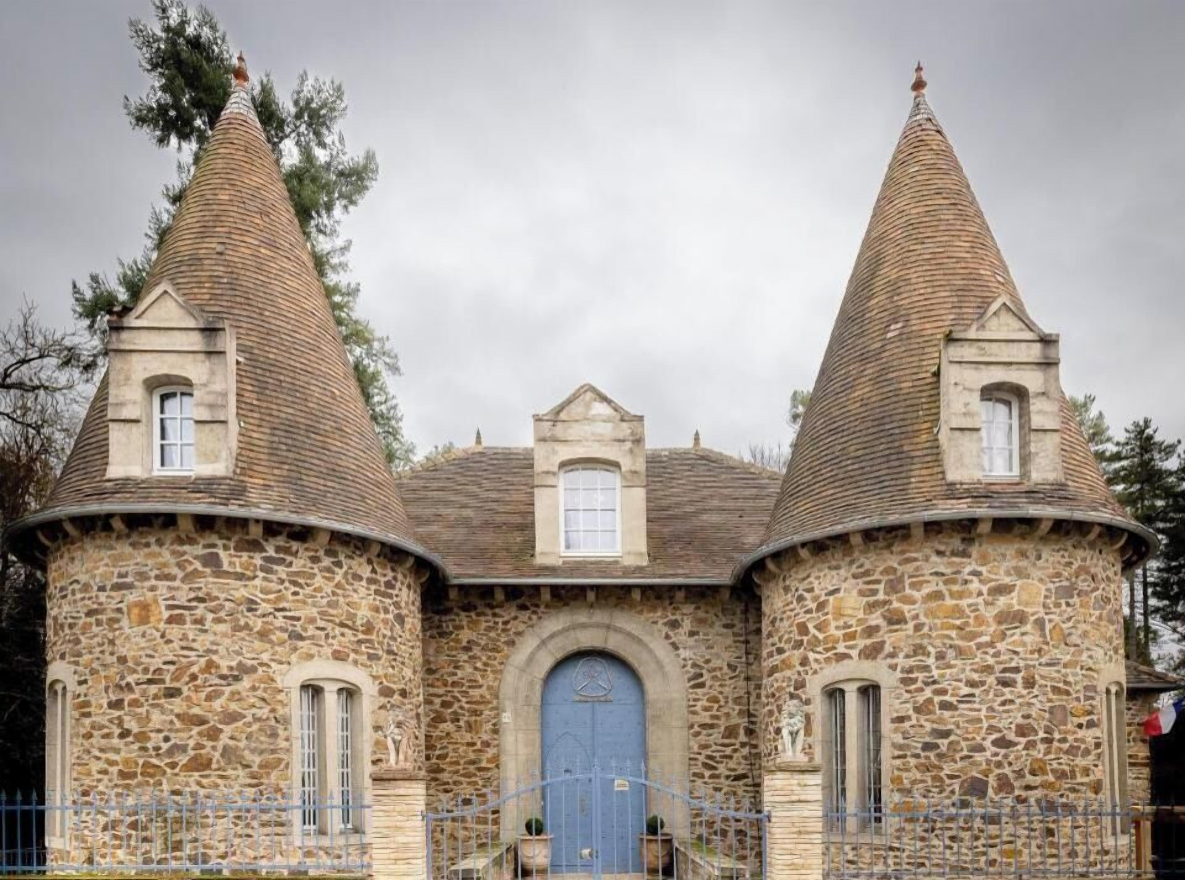 Un bâtiment en pierre doté d’une porte centrale et de deux tours coniques.