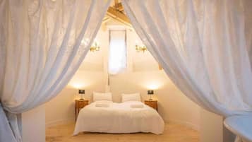 A bedroom with a canopy bed, two bedside tables, and a chandelier.