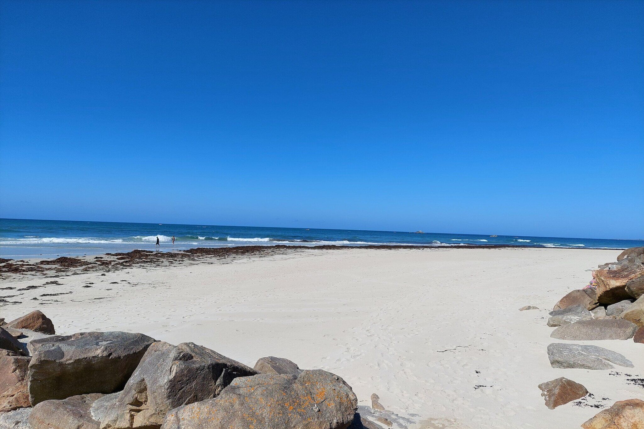 A beach with large rocks in the foreground and waves in the background.