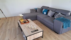 A modern living room with a grey sectional sofa, a wooden coffee table with decorative items, and a wooden floor. - House in Brittany with sea view for 2 people. (Cléder)