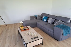 Ein modernes Wohnzimmer mit einem grauen Ecksofa, einem Holztisch mit Dekoration und einem Holzboden.