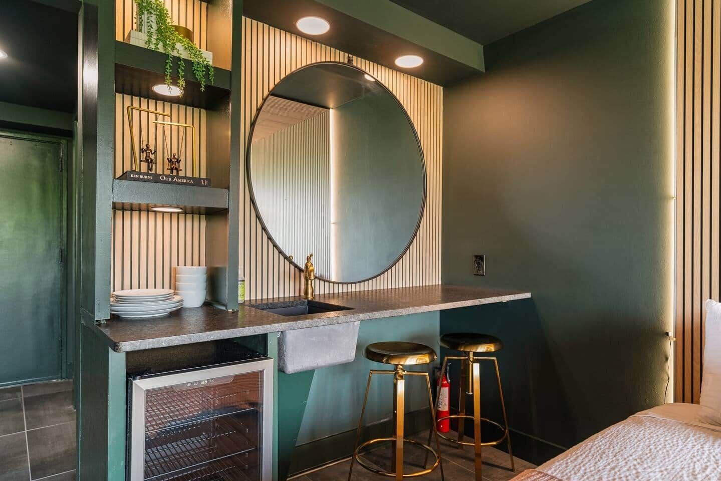 Une salle de bain avec un grand miroir, un lavabo, deux tabourets et un porte-serviettes.