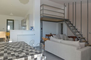 Ein modernes Interieur mit Essbereich, Sofa und Schlafgalerie mit Treppe.