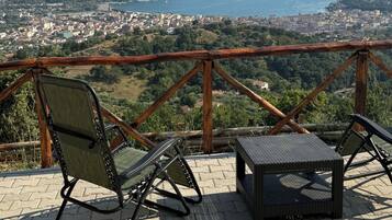 Eine Terrasse mit zwei Stühlen und einem kleinen Tisch mit Blick auf eine Küstenstadt und das Meer.