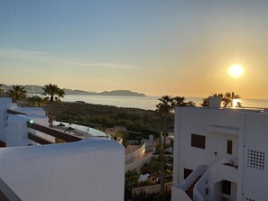 A coastal view with a sunset, white buildings, and palm trees. - Comfortable apartment, sea view - 6 guests (San Juan de los Terreros)