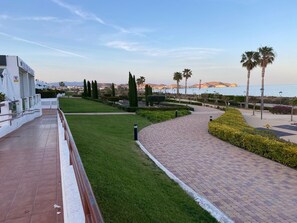 A landscaped promenade with a paved walkway, manicured grass, and palm trees. - Comfortable apartment, sea view - 6 guests (San Juan de los Terreros)