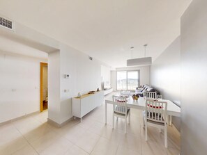 A modern kitchen with white cabinetry, a dining table with chairs, and a large window providing natural light. - Comfortable apartment with golf course view - 4 guests (San Juan de los Terreros)