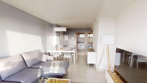 En moderne stue med sofa, sofabord og spiseområde med stole og bord.