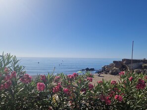 A beach with clear skies, calm sea, and rocky coastline.