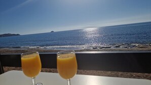 To glas appelsinjuice på et bord med havudsigt og en fjernd island.